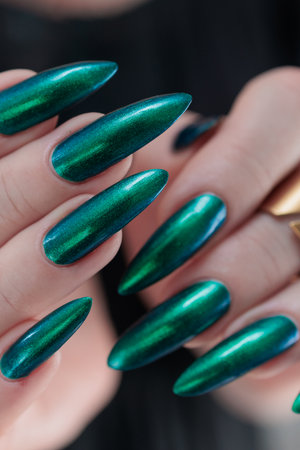 Woman's hand with long nails and green blue nail polishの写真素材