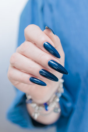 Woman's beautiful hand with long nails and dark blue manicureの写真素材