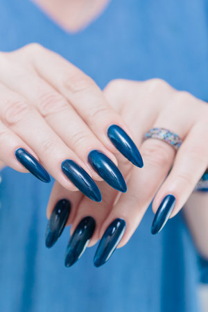 Woman's beautiful hand with long nails and dark blue manicureの写真素材