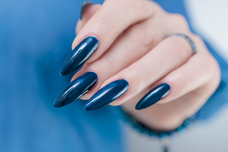 Woman's beautiful hand with long nails and dark blue manicureの写真素材