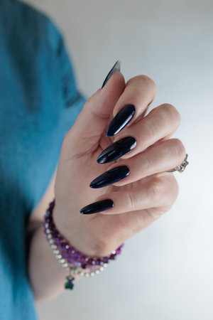 Woman's beautiful hand with long nails and dark blue manicureの写真素材