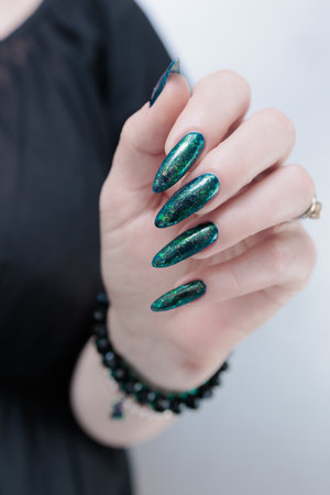 Woman's hand with long nails and green blue nail polishの写真素材