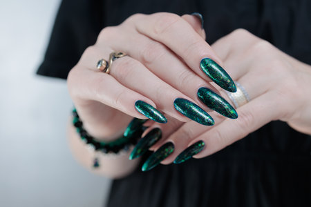 Woman's hand with long nails and green blue nail polishの写真素材