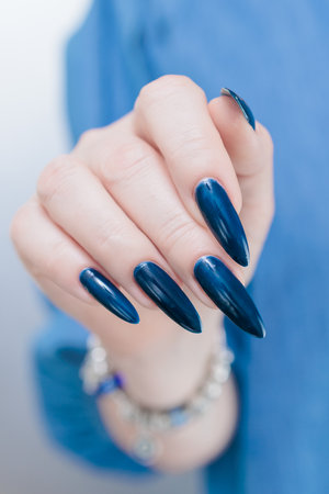 Woman's beautiful hand with long nails and dark blue manicureの写真素材
