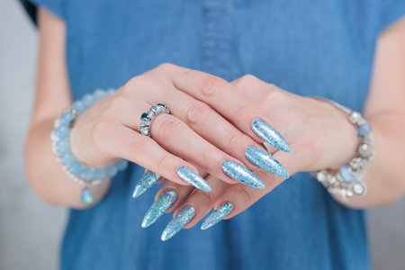 Female hand with long nails and bright light blue and silver manicureの写真素材