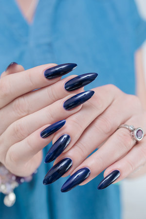 Woman's beautiful hand with long nails and dark blue manicureの写真素材