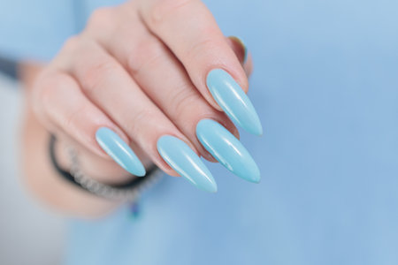 Woman's beautiful hand with long nails and baby blue manicureの写真素材