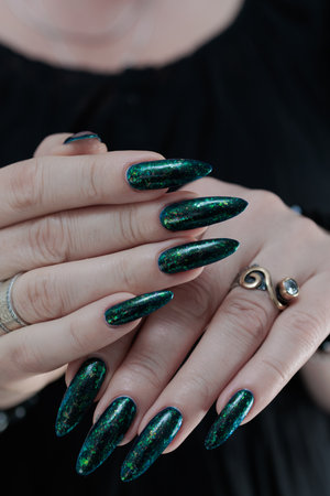Woman's hand with long nails and green blue nail polishの写真素材