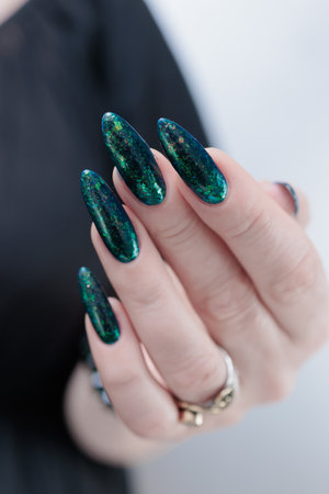 Woman's hand with long nails and green nail polishの写真素材