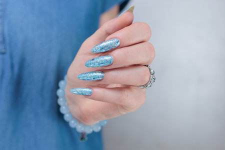 Female hand with long nails and bright light blue and silver manicureの写真素材
