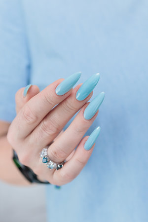 Woman's beautiful hand with long nails and baby blue manicureの写真素材