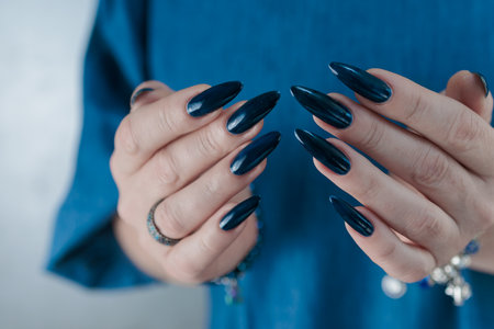 Woman's beautiful hand with long nails and dark blue manicureの写真素材