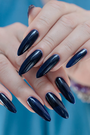 Woman's beautiful hand with long nails and dark blue manicureの写真素材