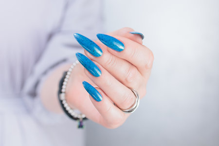 Woman's beautiful hand with long nails and bright blue manicureの写真素材