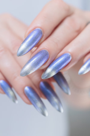 Female hand with long nails and bright light blue and silver manicureの写真素材