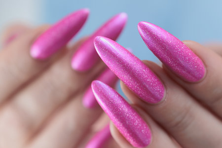 beautiful female hands with long nails and bright neon pink red nail polishの写真素材