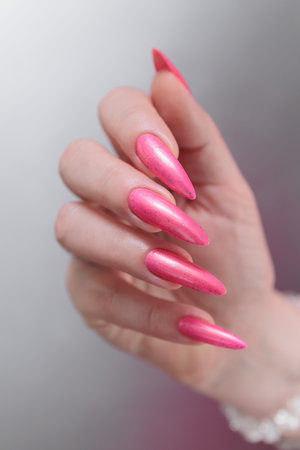 beautiful female hands with long nails and bright neon pink red nail polishの写真素材