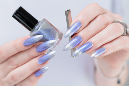 Female hand with long nails and bright light blue and silver manicureの写真素材