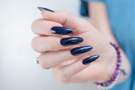 Woman's beautiful hand with long nails and dark blue manicureの写真素材