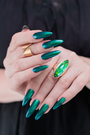 Woman's hand with long nails and green blue nail polishの写真素材