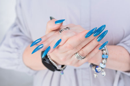 Woman's beautiful hand with long nails and bright blue manicureの写真素材