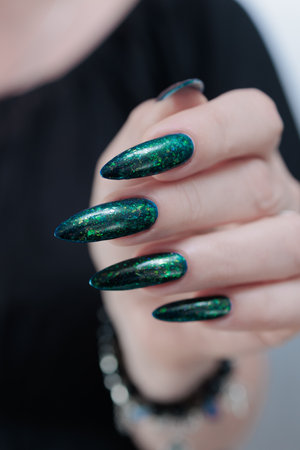 Woman's hand with long nails and green blue nail polishの写真素材