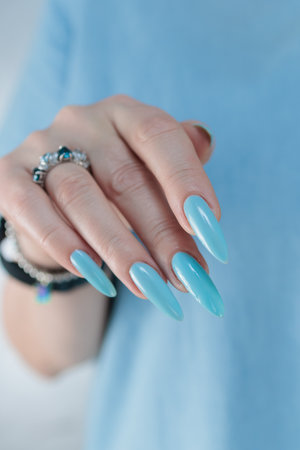 Woman's beautiful hand with long nails and baby blue manicureの写真素材