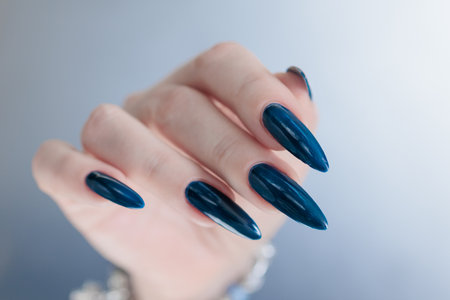 Woman's hand with long nails and dark blue manicureの写真素材