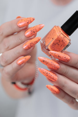 Hand with long nails and light orange neon manicureの写真素材