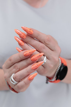 Woman hand with long nails and light orange neon manicureの写真素材