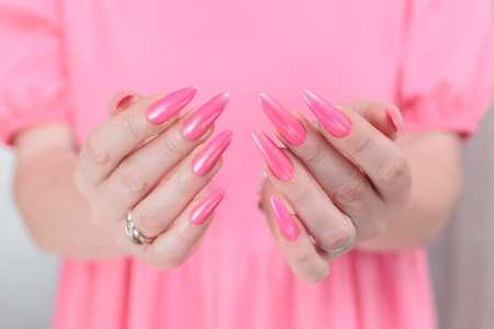 beautiful female hands with long nails and bright neon pink red nail polishの写真素材