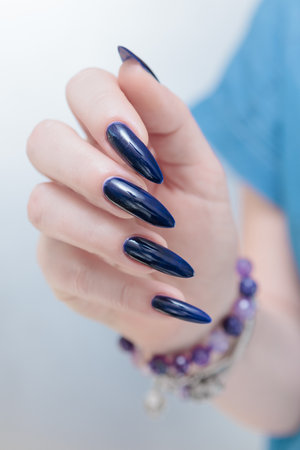 Woman's beautiful hand with long nails and dark blue manicureの写真素材