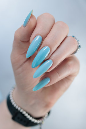 Woman's beautiful hand with long nails and baby blue manicureの写真素材