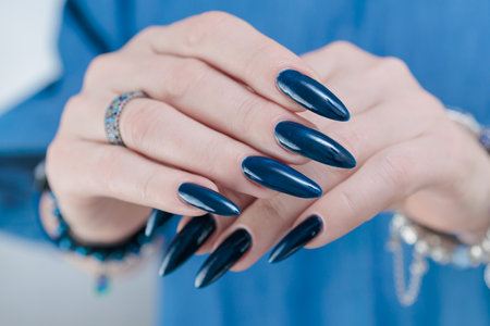 Woman's hand with long nails and dark blue manicureの写真素材