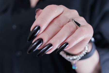 Female hands with long nails and black nail polishの写真素材