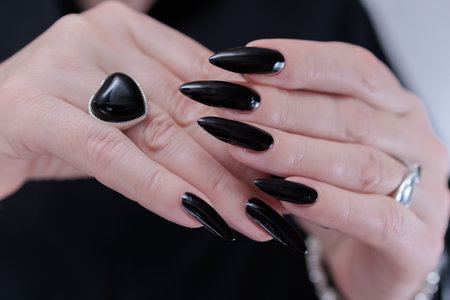 Female hands with long nails and black manicureの写真素材