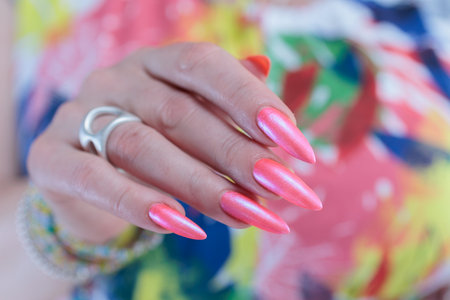 beautiful female hands with long nails and bright neon pink nail polishの写真素材