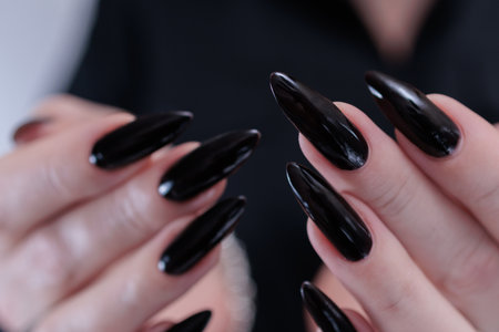 Female hands with long nails and black nail polishの写真素材