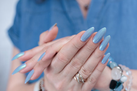 Woman's beautiful hand with long nails and light baby blue manicureの写真素材