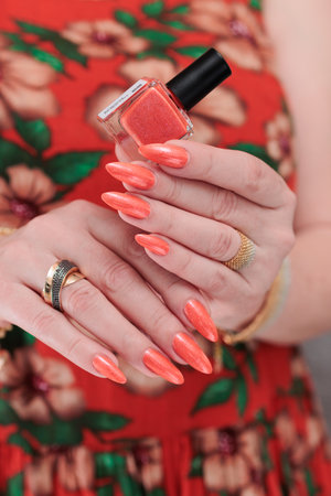 Female beautiful hand with long nails and a bright orange nail polish