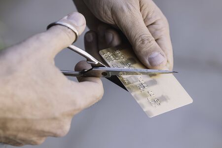 Hand cutting a credit card with scissorsの写真素材