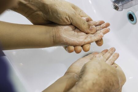 Dad washing his little son's hands with soap and waterの写真素材