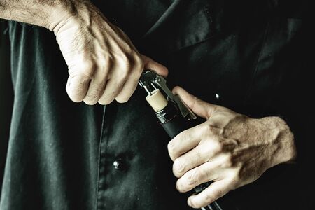 Male hands uncorking wine bottle