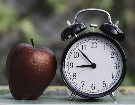 Alarm clock and red apple on books Conceptual back to schoolの写真素材