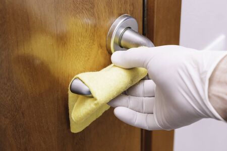 Hand with glove and cloth cleaning door handle Conceptual hygiene, protection against covid-19, coronavirusの写真素材
