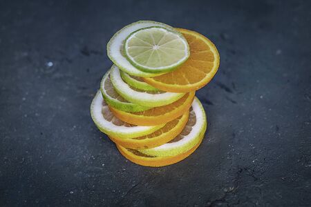 Citrus tower on dark background Orange, lime and lemon cut into slices in balanceの写真素材
