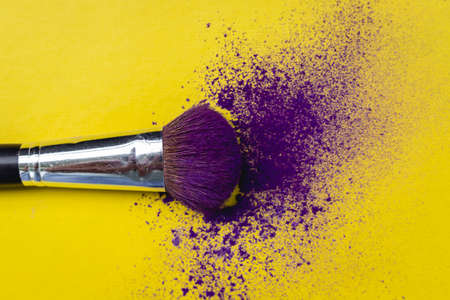 Brush with purple eyeshadow on yellow background Conceptual of beauty, personal careの写真素材
