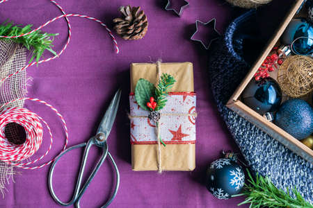 Still life of gift wrapped at home with Christmas objects Preparing Christmas gifts at home with scissors ribbons and twineの写真素材
