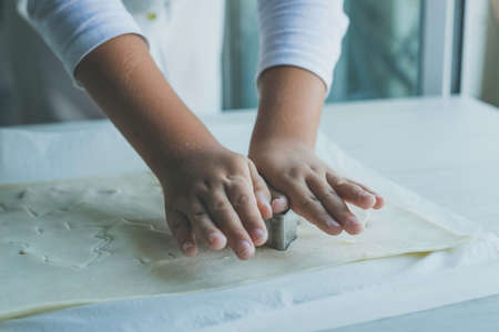 Child hands making christmas tree shaped cookies in fresh doughの写真素材