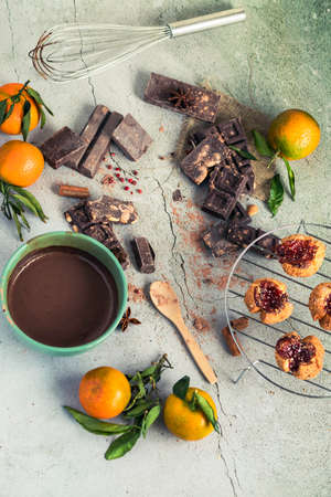 Spiced chocolates, homemade cookies and tangerines on white stone background